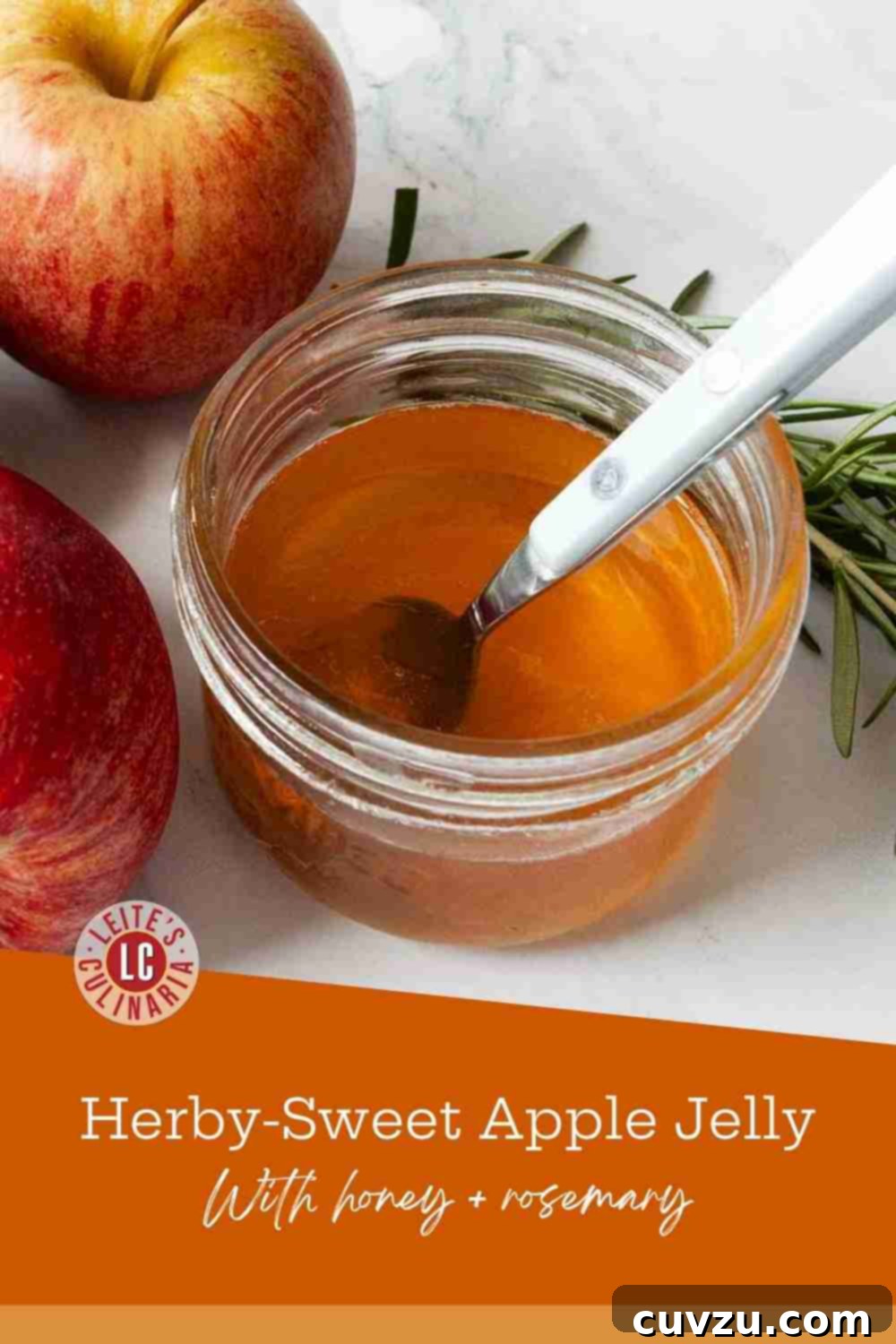 Orchard's Golden Jelly 3 Caramel-hued apple jelly glistens in a clear glass jar with a spoon, flanked by vibrant red apples and a fresh rosemary sprig, showcasing its natural beauty.