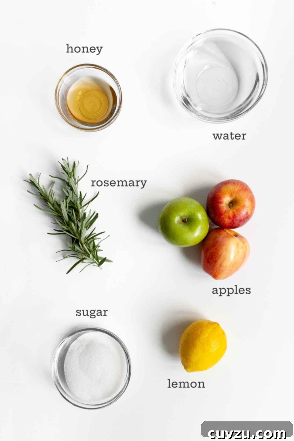 Orchard's Golden Jelly 5 A beautifully arranged flat lay of ingredients for apple jelly, featuring golden honey, fresh water, fragrant rosemary sprigs, crisp apples, sparkling sugar, and a vibrant lemon.