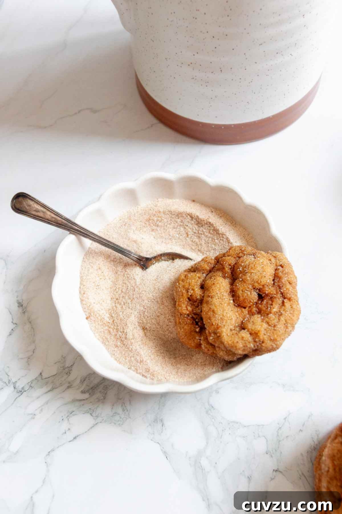 Golden Harvest Spice Cookies 8 A pumpkin spice cookie resting on the edge of a bowl of spiced sugar.