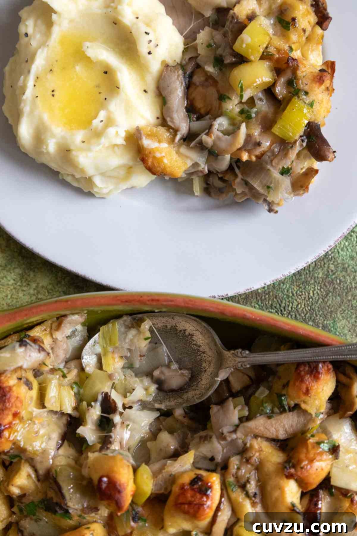 An oval casserole dish filled with wild mushroom stuffing, alongside a plate of stuffing and mashed potatoes.