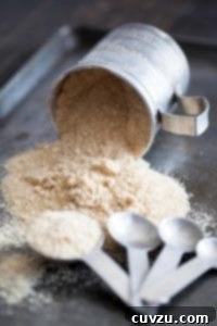 A tin cup on its side with homemade maple sugar spilling out, displaying its beautiful, granulated texture