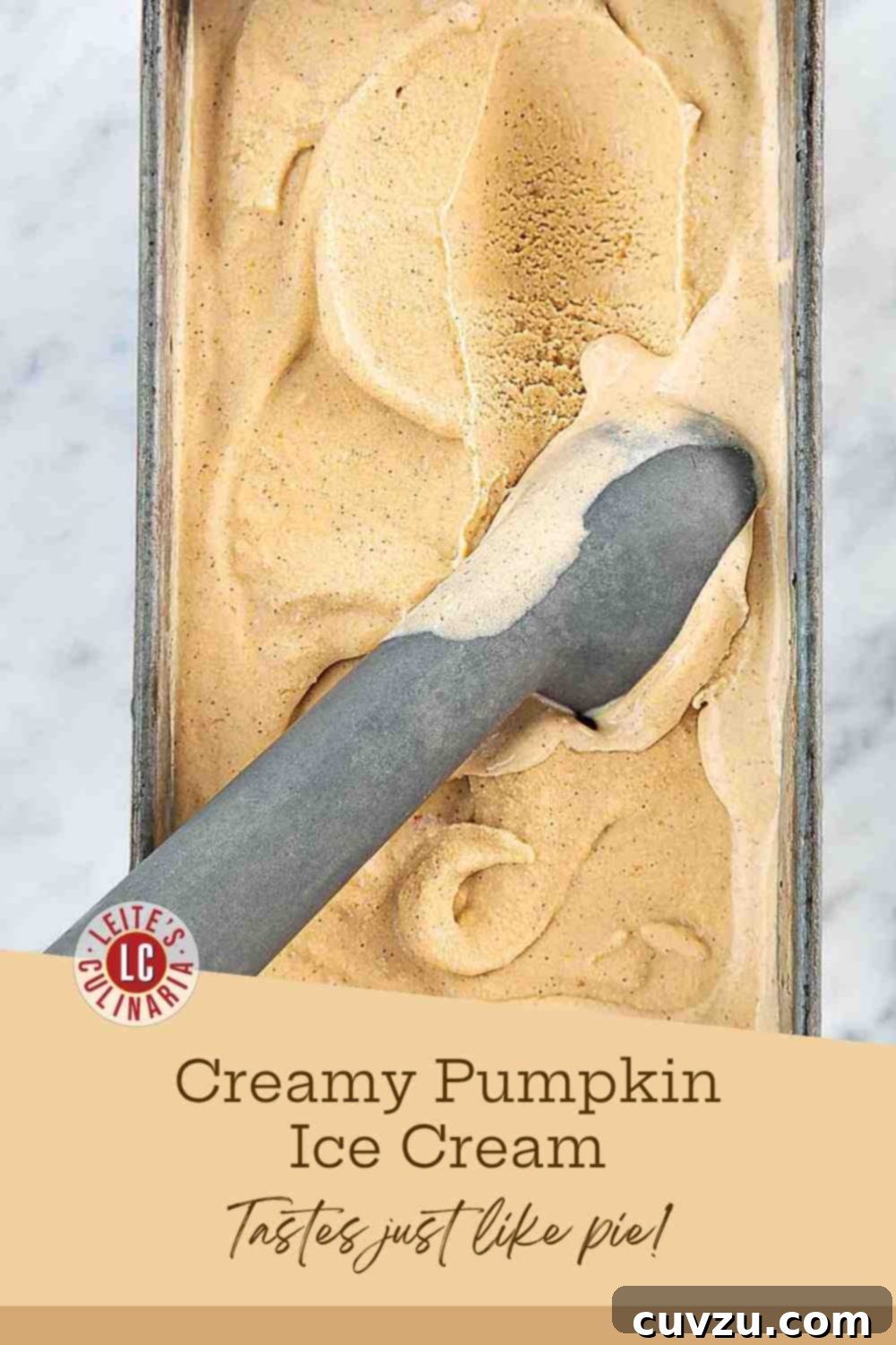 Spiced Pumpkin Dream 3 A metal ice cream scoop elegantly rests inside a rustic loaf pan brimming with creamy, spiced pumpkin custard ice cream, showcasing its irresistible texture.