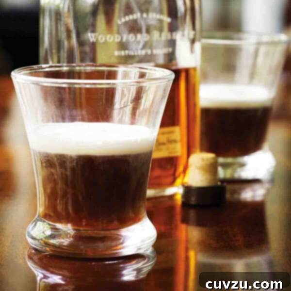 Two glasses half-filled with Kentucky coffee and an open bottle of bourbon between them, highlighting the key ingredients.