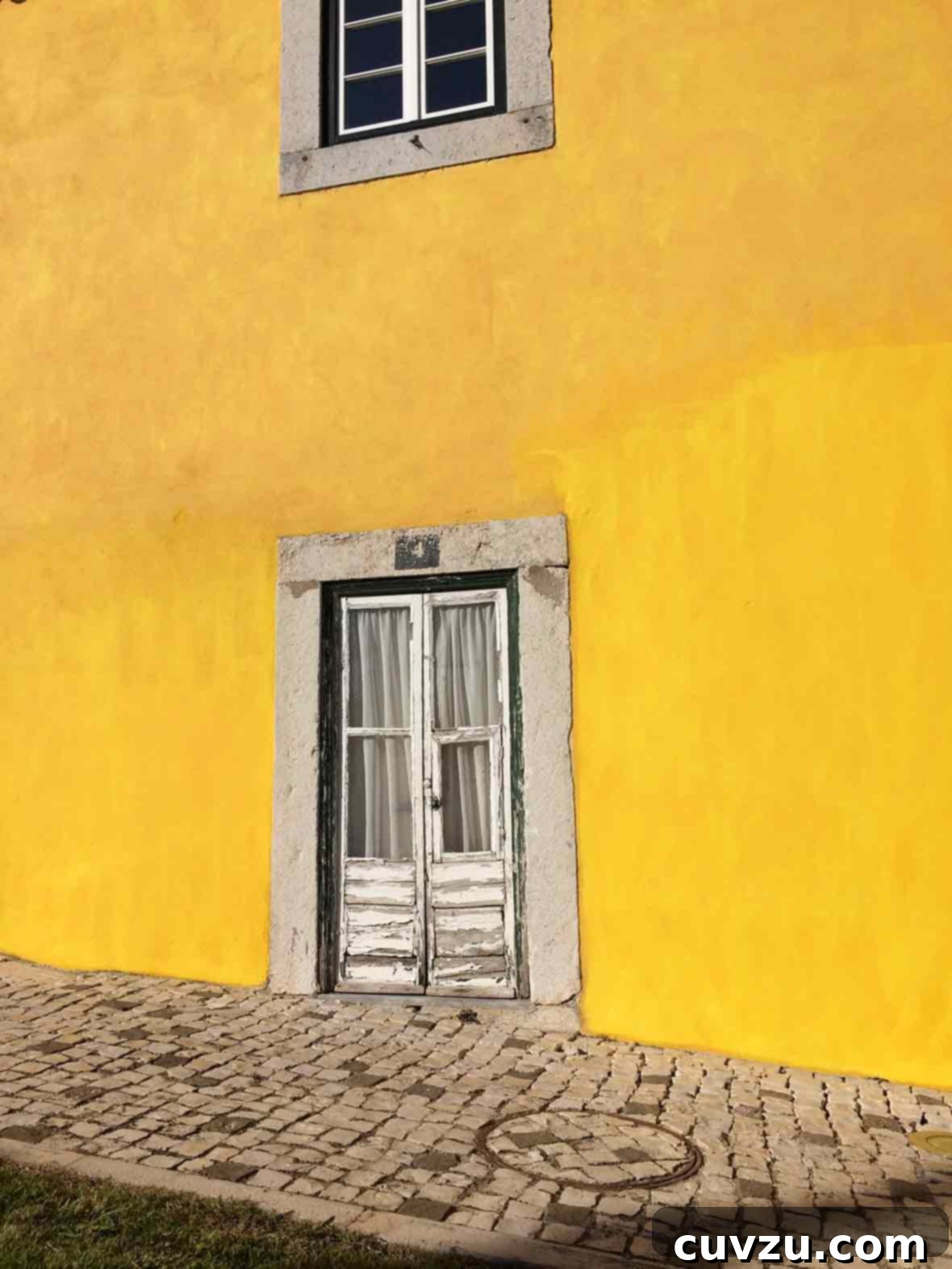 Lisbon's Golden Homecoming 4 A vibrant yellow wall featuring an old, weathered wooden door with intricate details, reflecting Lisbon's historic charm.