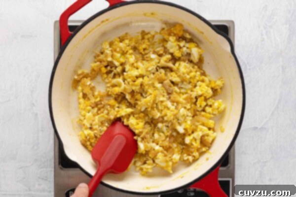 Egg Salad Reinvented 14 A person stirring a skillet filled with egg salad.
