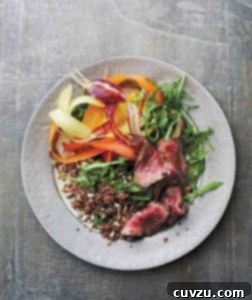 A grey plate topped with steak and quinoa salad with shaved carrots and mustard vinaigrette.