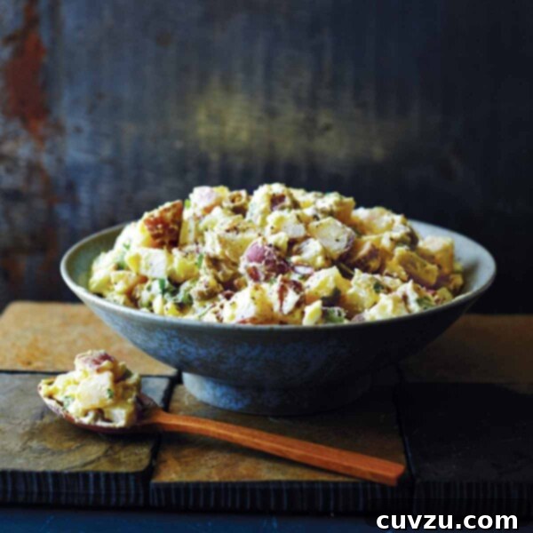 A bowl filled with Southern potato salad, perfectly dressed and ready to be served, with a wooden spoon and a small portion on the side.