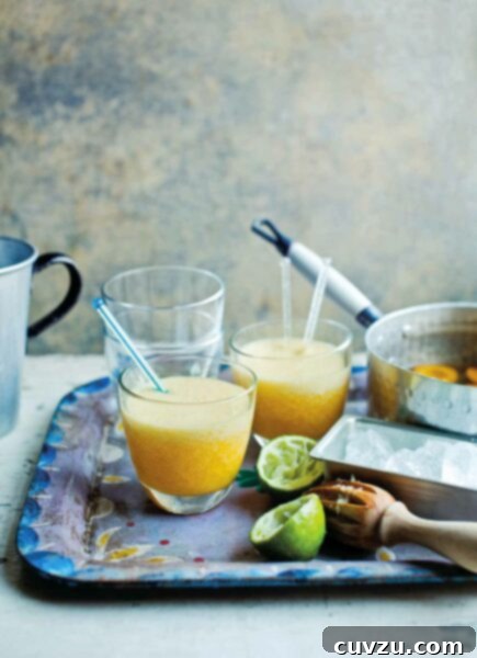 A metal serving tray with two apricot daiquiris with stir sticks, a juiced lemon, and a pot with poached apricots.