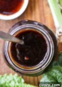 A glass jar filled with homemade Korean barbecue sauce, with fresh green garnishes beside it.