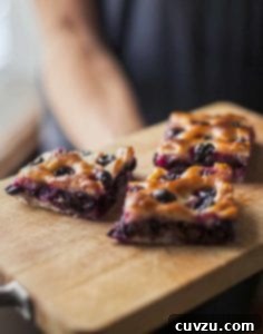 Three pieces of grape focaccia on a wooden board.