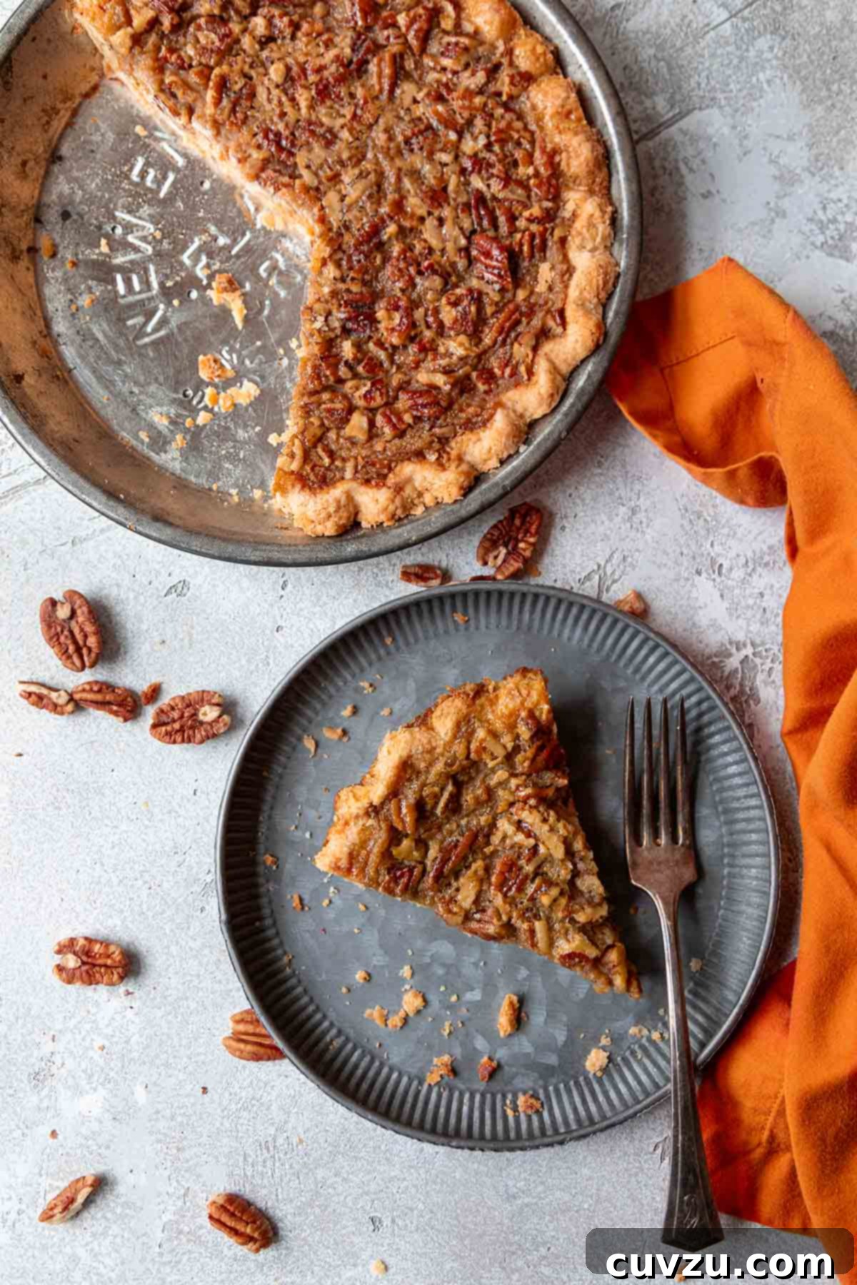 Autumn Spice Pumpkin Pecan Pie 8 A perfectly sliced piece of pumpkin pecan pie rests on a small plate, positioned next to the remainder of the pie, still in its baking dish, showcasing its inviting texture and distinct layers.