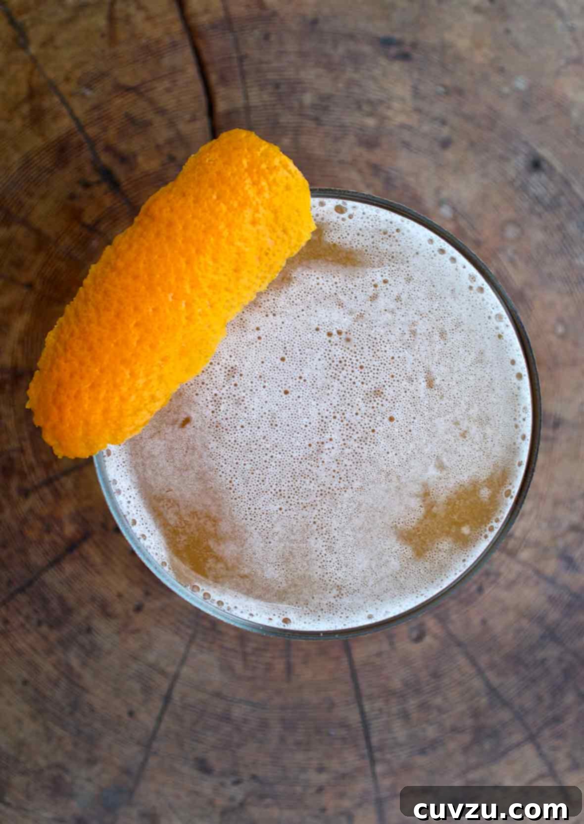 Spiced Apple Elixir 3 An overhead view of a down Easter cocktail, topped with a strip of orange zest.