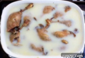 A white oval casserole dish filled with duck confit legs.