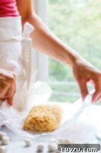 A woman holding a small batch of Rice Krispies treats for two on a piece of wax paper.