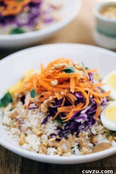 A close-up of a healthy Gado Gado Salad, showing the rich colors and textures of the ingredients, coated in a luscious peanut sauce.