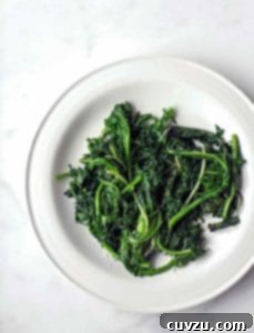 A pile of charred greens--kale and spinach--on a white plate.