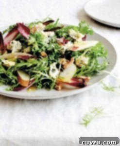 Endive Blue Cheese Pear Salad 3 A white plate topped with endive, blue cheese, pears, and walnuts