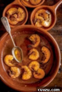 Three crockery bowls filled with cooked shrimp with smoked paprika oil