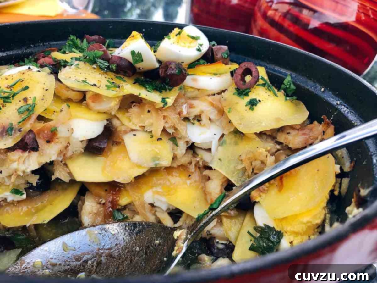 Portugal's Iconic Salt Cod Bake 10 Ilda's rendition of Bacalhau à Gomes de Sá, showing the distinct layers of salt cod, potatoes, and onions, adorned with sliced olives, quartered boiled eggs, and fresh parsley.