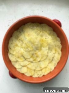 Portugal's Iconic Salt Cod Bake 8 Another layer of thinly sliced potatoes, seasoned with olive oil, salt, and pepper, covering the previous layers in the Bacalhau à Gomes de Sá casserole.
