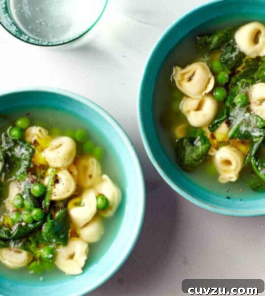 Two bowls filled with easy tortellini soup with peas and spinach.