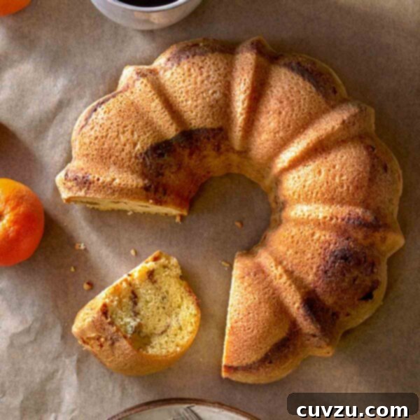 A beautifully baked Zingerman's sour cream coffee cake, a slice perfectly cut and resting beside a cup of freshly brewed coffee, surrounded by serving plates and forks.