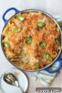 Blue casserole of spicy macaroni and cheese with breadcrumbs on top and sliced of jalapeno peppers.