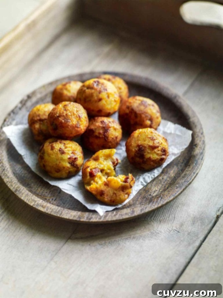Golden Chouriço Potato Bites 2 A wooden bowl filled with golf-ball-size fried potato and chouriço balls on a wooden tray