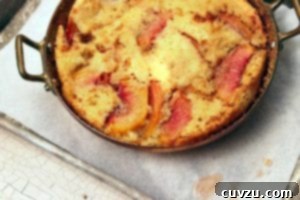 A pan with two handles filled with a Southern peach cobbler on a baking sheet