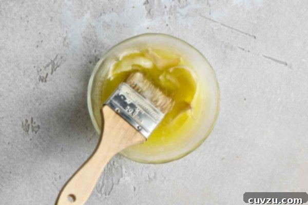 A bowl of garlic butter with a brush inside.