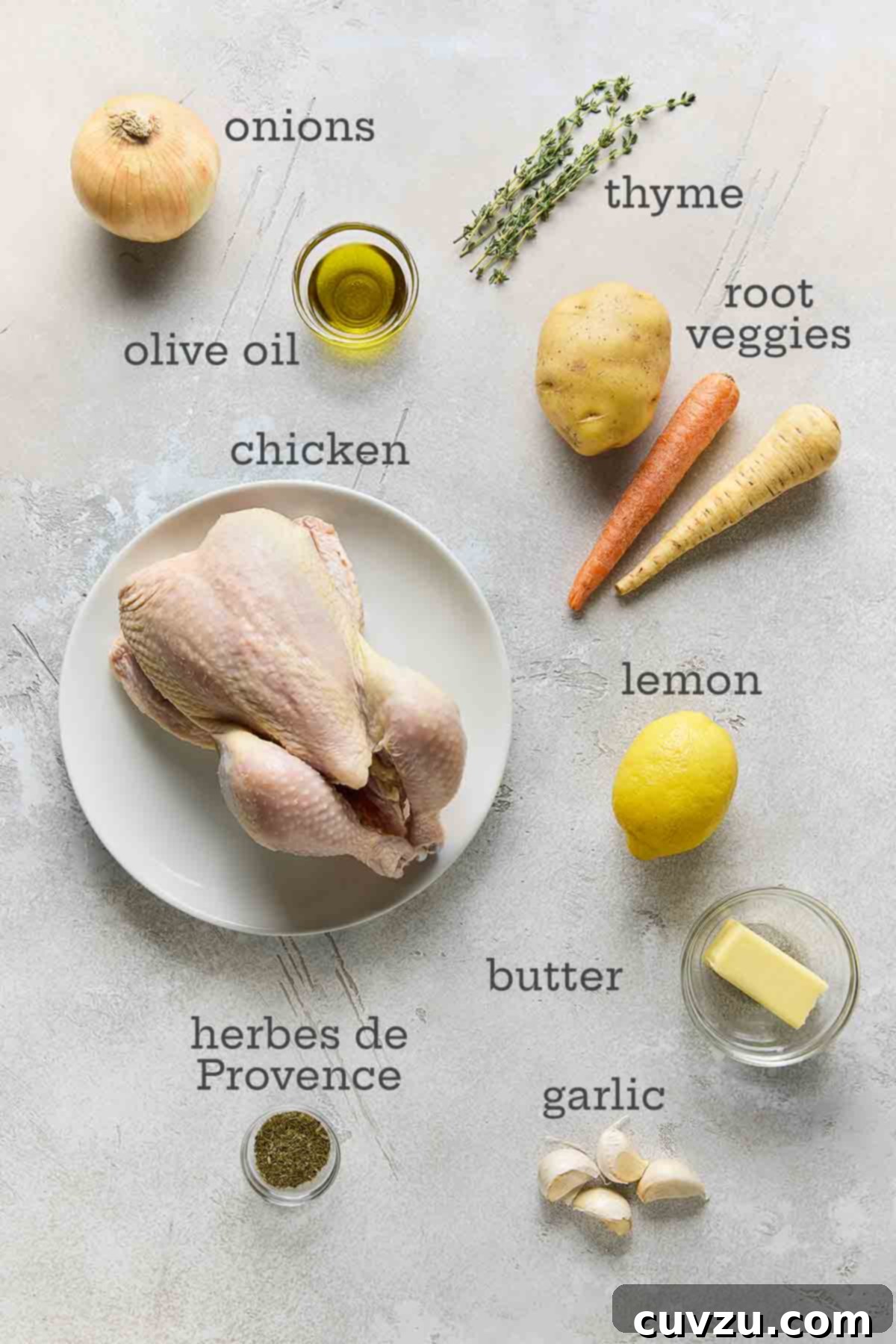 Classic French Roast Chicken 4 A vibrant selection of ingredients laid out for French roast chicken: a whole chicken, onions, various root vegetables, fresh thyme, lemons, butter, garlic, and olive oil.
