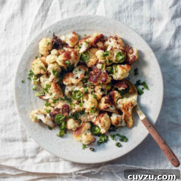 A white plate topped with roasted cauliflower with jalapeño and capers, beautifully arranged and ready to be enjoyed.