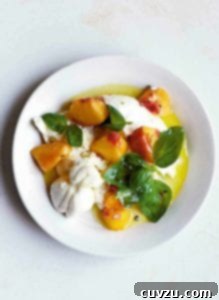 Sun-Kissed Peach Burrata Bliss 3 A white bowl filled with peach, burrata, and basil salad, showcasing its fresh ingredients and vibrant colors.