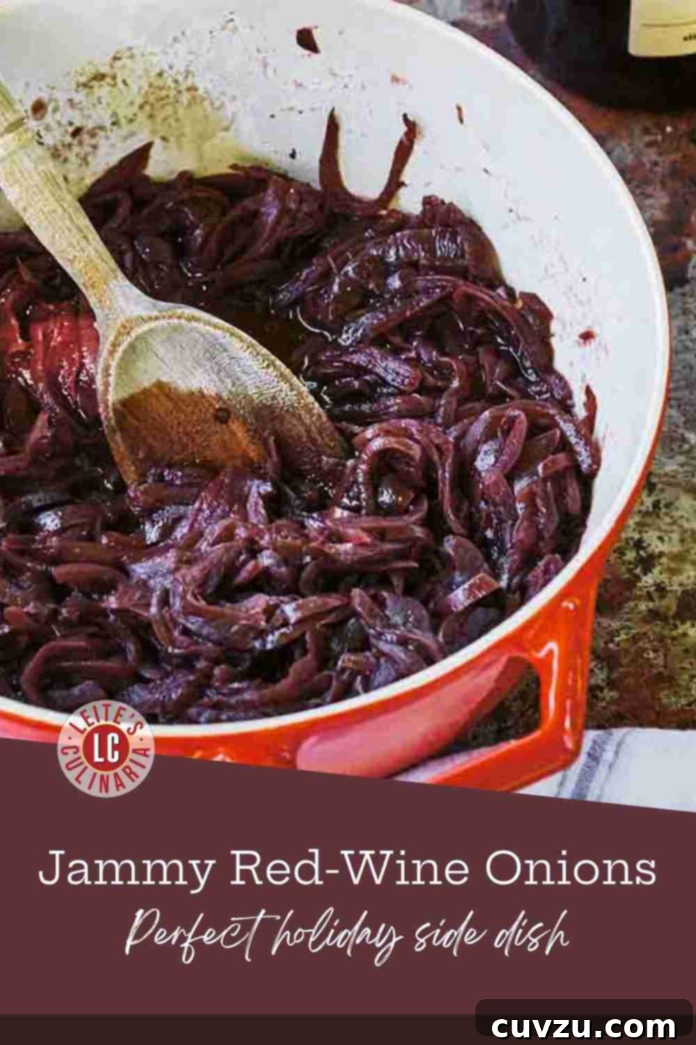 Caramelized Red Wine Onions 3 Close-up of glossy, deep purple-red caramelized onions in a small white pot with a wooden spoon, next to fresh red onion halves, illustrating the rich texture and color.
