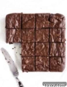 A batch of Rose Levy Beranbaum's fudge brownies cut into 16 squares, with two missing and a knife resting beside.