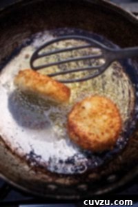 Old frying pan with two leftover mashed potato cakes being turned by a spatula.
