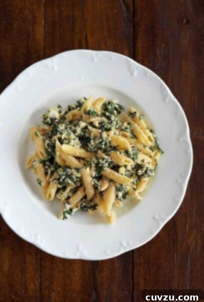Velvety Spinach Ricotta Penne 3 A white serving bowl filled with penne with spinach-ricotta sauce, garnished with fresh herbs and a sprinkle of Parmesan.