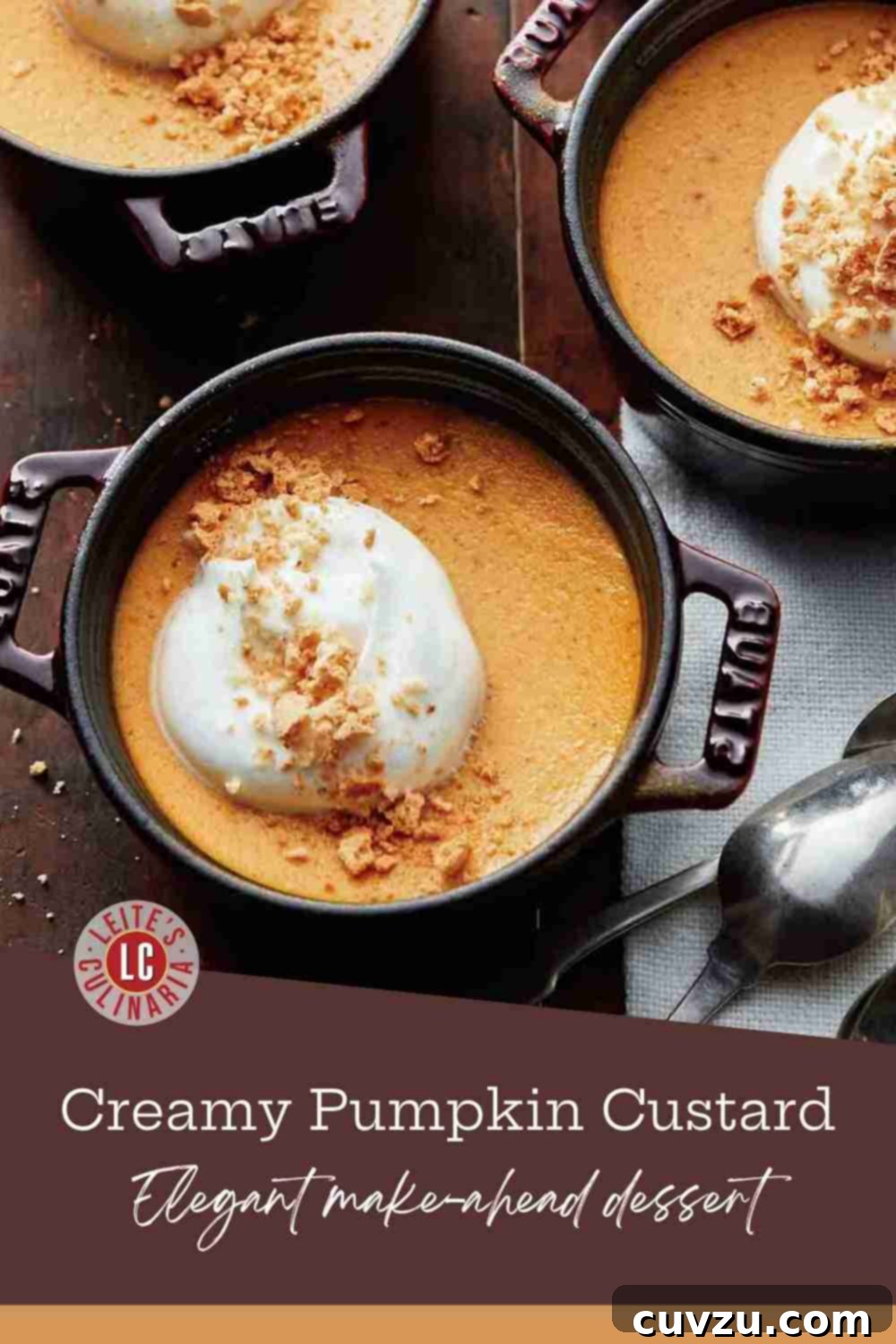 Three small, dark cocottes brimming with rich pumpkin custard, generously topped with fluffy maple whipped cream and crunchy amaretti cookie crumbles.