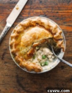 A mini homemade chicken pot pie with a flaky crust, chunks of white meat chicken, and peas