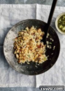A decorative metal serving bowl filled with fried rice with leftovers and a bowl of jalapeño garlic vinegar on the side