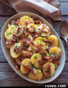 An oval serving bowl filled with German potato salad, ready to be served.