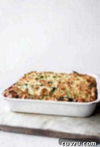 A white baking dish filled with golden-brown zucchini strata, a perfect vegetarian meal that is both comforting and elegant.