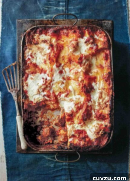Meatball lasagna, with one piece missing, in a large baking dish beside a spatula.