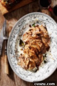 A black and white decorative platter filled with Tuscan roast pork and scattered with bay leaves