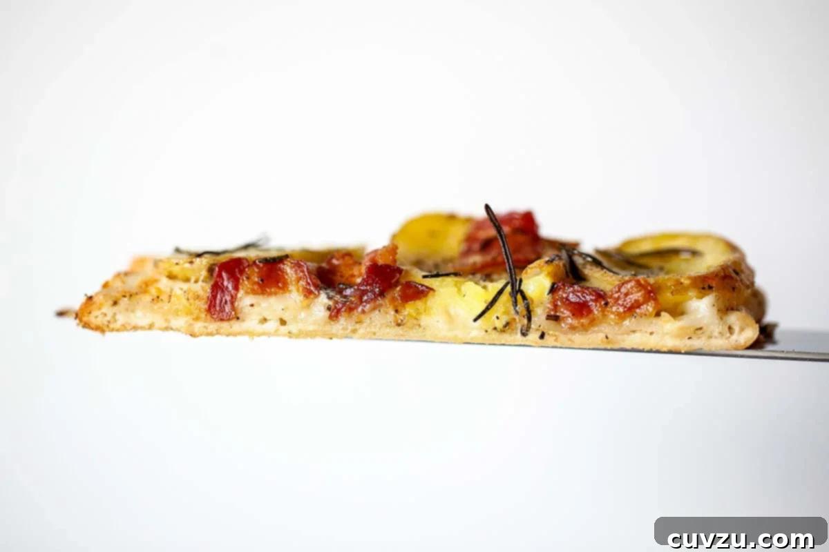 Farmhouse Potato Bacon Pizza 3 A slice of potato bacon pizza on a peel.