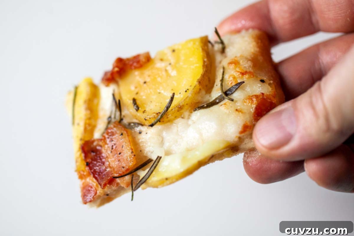 Farmhouse Potato Bacon Pizza 4 A person holding a slice of potato bacon pizza.