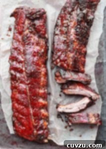 Two slabs of honey teriyaki ribs, one partially cut into ribs on a sheet of parchment.
