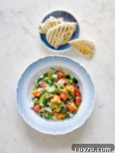 A close-up of the refreshing melon and avocado salad in a rustic blue and white bowl.