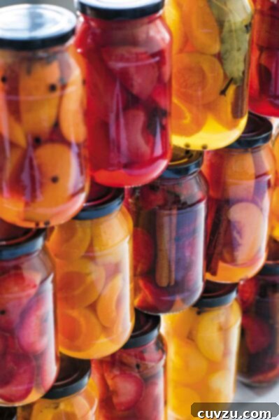 An assortment of pickled stone fruits in jars stacked on top of each other.