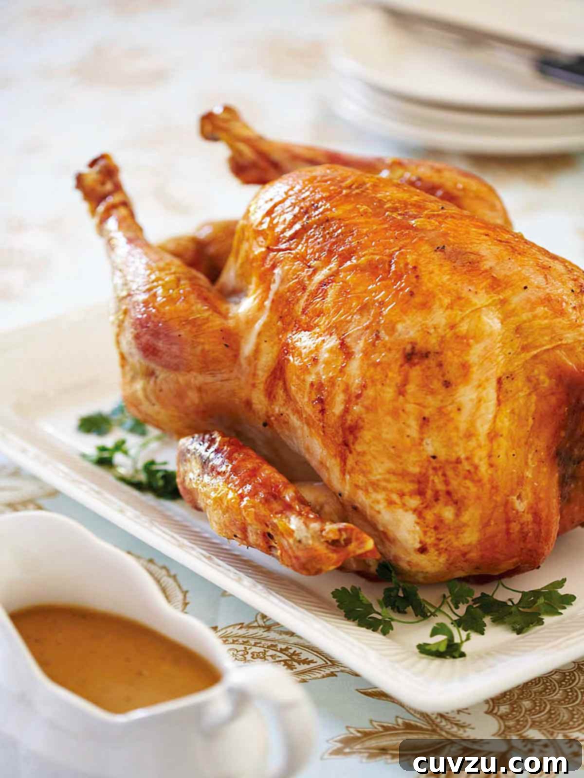 Heritage Roast Turkey and Velvety Gravy 2 An old-fashioned roast turkey on a white platter, with gravy in a boat beside it.